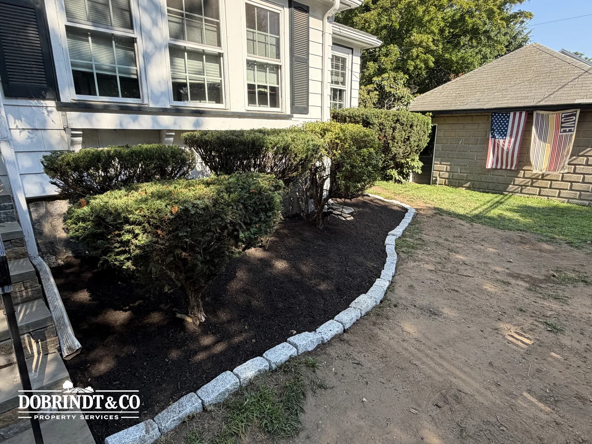 Residential property with trimmed bushes and a gravel path leading to the front of the house.
